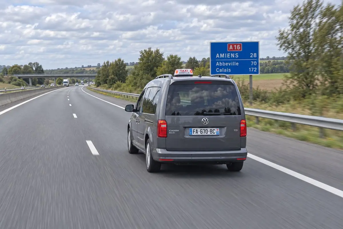 Le taxi JB TRANSPORT sur l’autoroute A16, sous le panneau Amiens, Abbeville, Calais