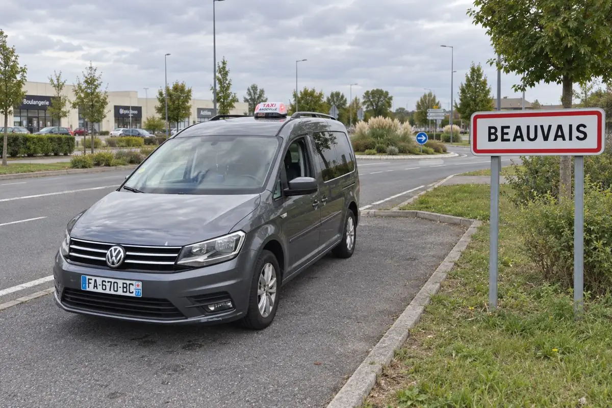 Le taxi JB TRANSPORT garé près du panneau d’entrée de Beauvais