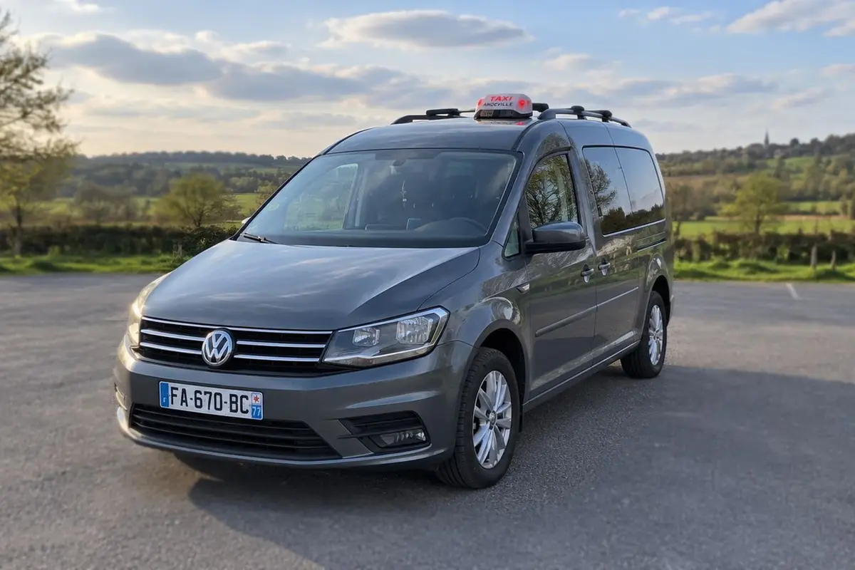 Le taxi JB TRANSPORT, un Volkswagen Caddy Maxi gris, garé en pleine campagne